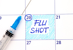 calendar marking date to get flu shot with epidermic needle laid on top